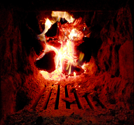 Photo of fire brown wood dark gray black coals on bright yellow fire inside metal brazier.Wood...