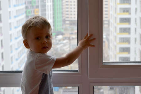 Beautiful baby boy with child face posing photographer near window for color photo. Cadre consisting of baby boy in child image near window, caucasian expression. Healthy baby boy it child near windowの写真素材