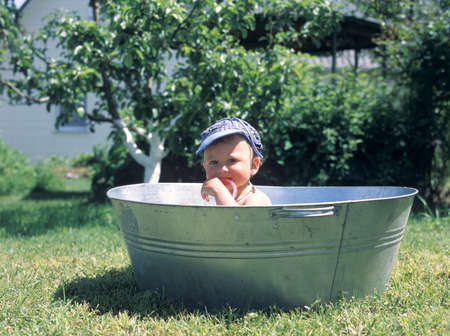 Beautiful baby boy in child tub posing photographer for color photo. Cadre consisting of baby boy on child tub, caucasian expression face. Healthy baby boy with child tub relaxing for colorful shot.の写真素材