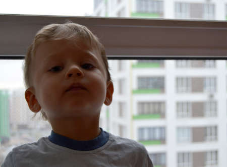 Beautiful baby boy with child face posing photographer near window for color photo. Cadre consisting of baby boy in child image near window, caucasian expression. Healthy baby boy it child near windowの写真素材