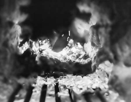 Beautiful old fireplace with light flame fire for heating building room, old fireplace consisting of thick oak wooden logs in hot flame fire, bright flame fire in old iron fireplace from slice treeの写真素材