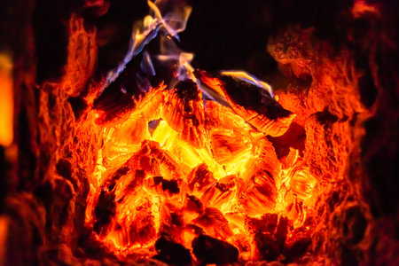 Beautiful old fireplace with light flame fire for heating building room, old fireplace consisting of thick oak wooden logs in hot flame fire, bright flame fire in old iron fireplace from slice treeの写真素材