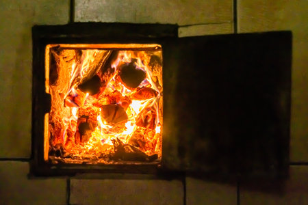 Beautiful old fireplace with light flame fire for heating building room, old fireplace consisting of thick oak wooden logs in hot flame fire, bright flame fire in old iron fireplace from slice treeの写真素材