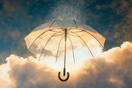 A colorful umbrella is held aloft in the sky, where raindrops cascade around it. Thick clouds surround the scene, adding a dramatic effect to the natural displayの素材