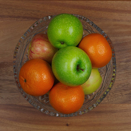 crystal vase with apples and oranges on wooden backgroundの写真素材
