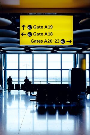 Cross process toned image of airport lounge with waiting people silhouettes. Heathrow airport, Great Britain.のeditorial素材
