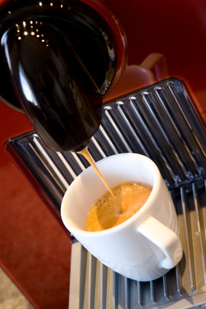 Fashionable automatic coffee machine pouring a fresh classic italian espresso in a small porcelain cupの写真素材