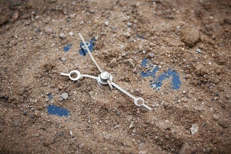 Old alarm-clock covered by layer of sandy soil
