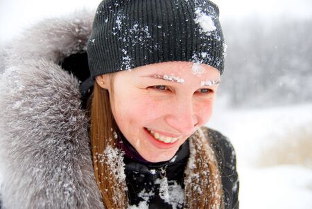 laughing girl with snow on her face staying in a winter woodsの写真素材