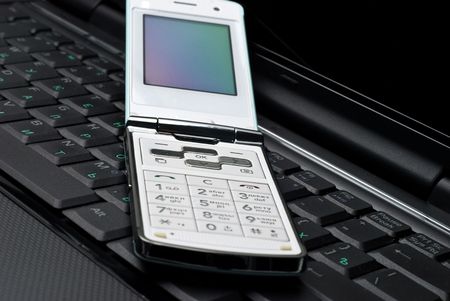 Cellular phone on a laptopの写真素材