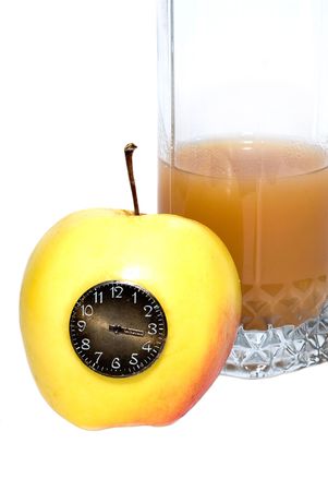glass of juice behind the yellow apple with the clockの写真素材