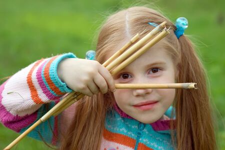 A little girl on a green meadow dressed warmly in a cold summer dayの写真素材