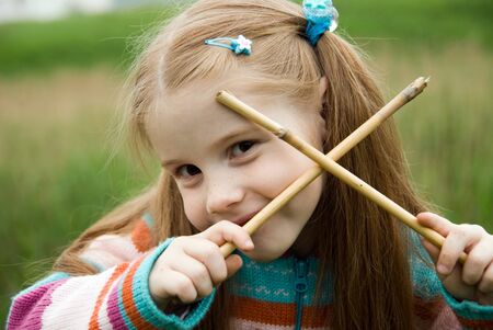 A little girl on a green meadow dressed warmly in a cold summer dayの写真素材