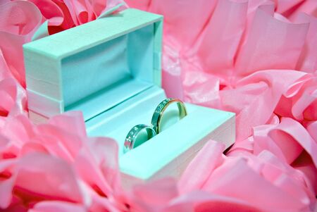two wedding bands in a white box and pink ribbons at backgroundの写真素材