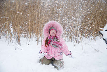 little girl playing with snow in a winter woodsの写真素材