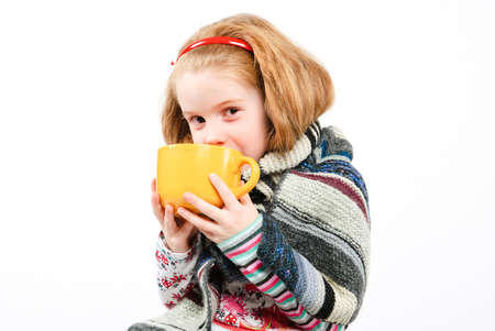 studio shot of pretty little girl with a cold holding a cupの写真素材
