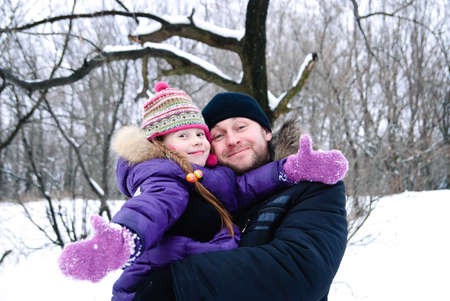 father and daughter in winter clothing in a winter woodsの写真素材