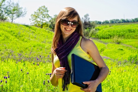 Smiling beautiful woman with laptop outdoor. Sunny summer day.の写真素材
