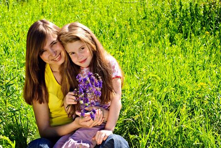 Smiling young mother with little daughter outdoor. Sunny summer day.の写真素材