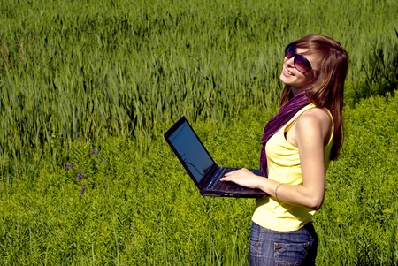 Young beautiful woman with laptop outdoor. Sunny summer day.の写真素材