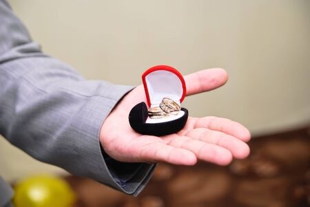 Hand of groom holding a box with a wedding bandsの写真素材