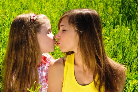 Kissing young mother and little daughter outdoor. Sunny summer day.の写真素材