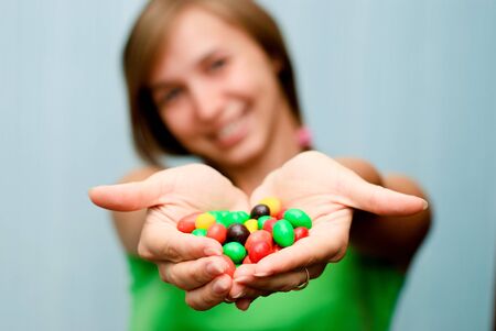 Portrait of a young woman offering colorful candiesの写真素材