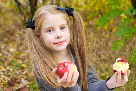 Little girl eating apple outdoorsの写真素材