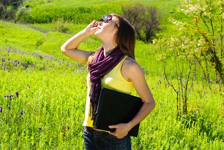 Young beautiful woman with laptop outdoor. Sunny summer day.の写真素材