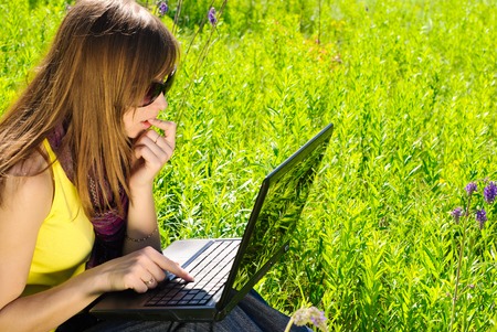 Young beautiful woman with laptop outdoor. Sunny summer day.の写真素材