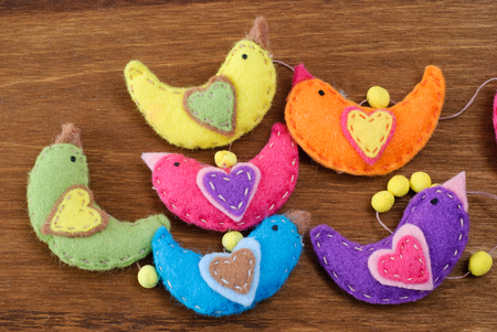 Several birds made of felt on a wooden background, Handmade arts and crafts project.の写真素材