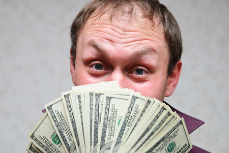 The rich man smiles and shows off bundles of hundred-dollar bills.の写真素材
