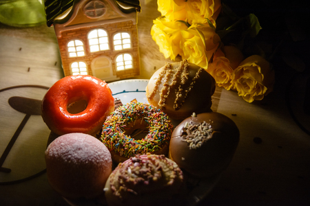 Various beautiful donuts and flowers in the evening home decorの写真素材