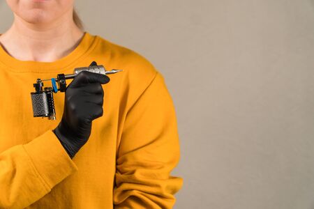 girl holds a stylish tattoo machine black permanentの写真素材