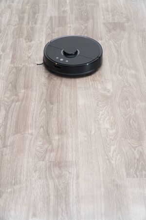 Robot vacuum cleaner black on the floor is cleaning, gray laminateの写真素材