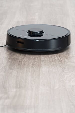 Robot vacuum cleaner black on the floor is cleaning, gray laminateの写真素材