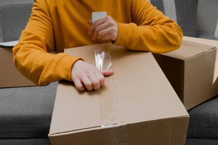 female hands paste a cardboard box closeup on a light background with tapeの写真素材