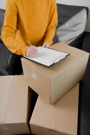 girl puts a signature on the form of delivery of things. Things are packed in cardboard vertical photoの写真素材