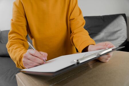 girl fills out an order form to send the parcel. A cardboard box is sent to the customerの写真素材