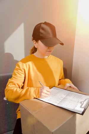 on a sunny day The girl fills out an order form to send the parcel cardboard boxの写真素材