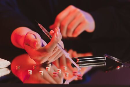 closeup female hand holds a syringe with drugs. The concept of social problems. Drug use and abuse...