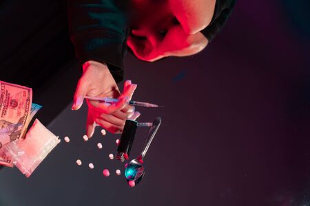 the average plan a young girl holds a syringe in her hand on a mirrored table. concept against...