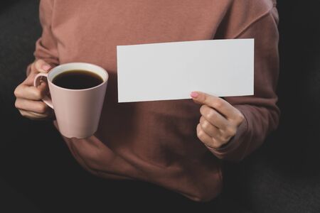 Middle aged woman hand holds white paper for text inscription. glass of wine in female hand. home stay idle concept.の写真素材