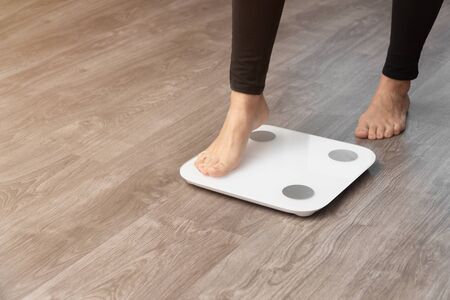 a girl in leggings wants to stand with one foot on the scales. concept of frustration with seen weight.の写真素材