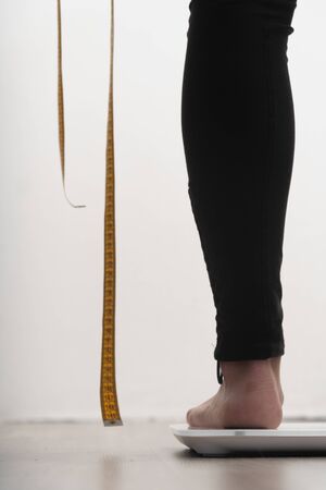 vertical photo of cropped female legs. hands holding a measuring tape. the concept that you need to...