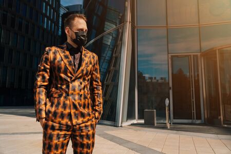 Portrait of a young man in medical black mask looking away forward against the background of business center. middle planの写真素材