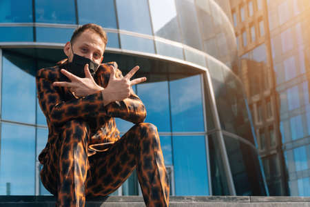 Portrait of a cheerful European man in a medical mask on the background of a business center. middle...