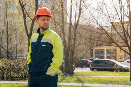 Young male builder in professional clothes looks away. construction thought conceptの写真素材
