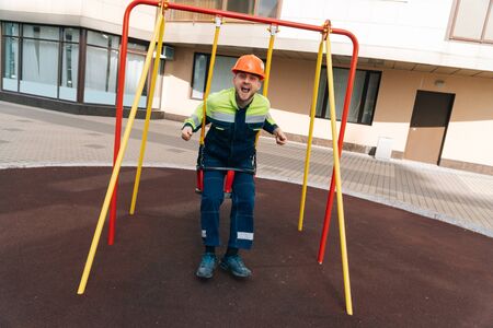 builder is swinging on swing at the playground of the future multi-story building. concept of riding...