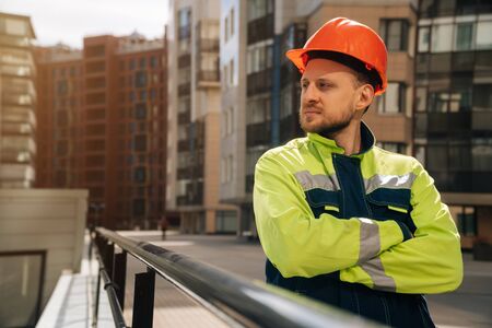 European man smiles in special clothes against the background of abusiness center. builder is glad that the work is overの写真素材